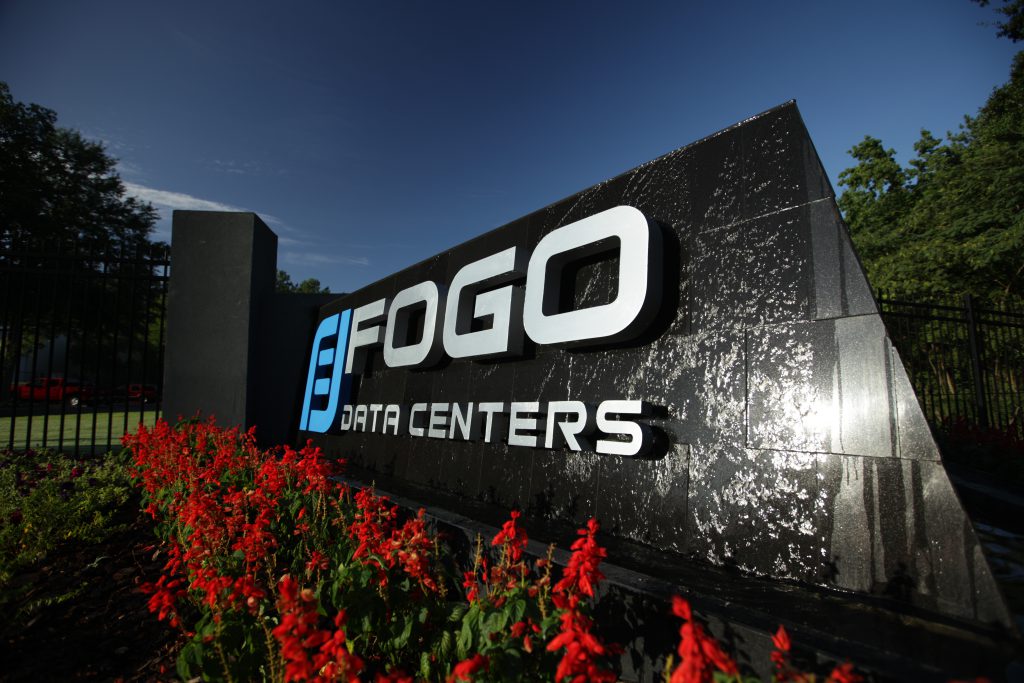 A sign for fogo fitness centers in front of flowers.