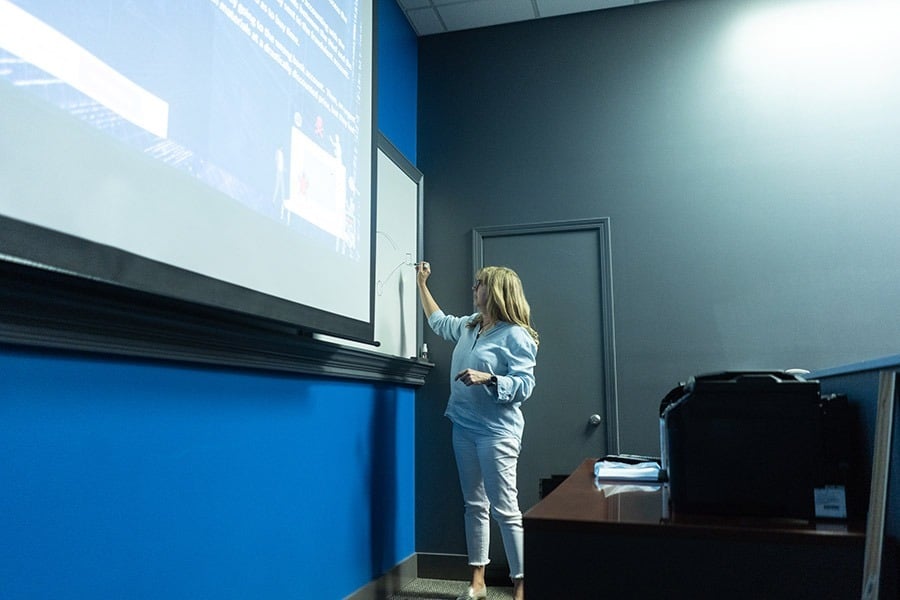 A businesswoman giving a presentation on cybersecurity in a classroom.