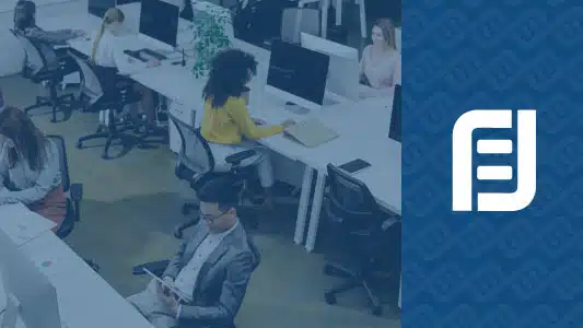 Employees engage in cybersecurity awareness training at desks in an office.