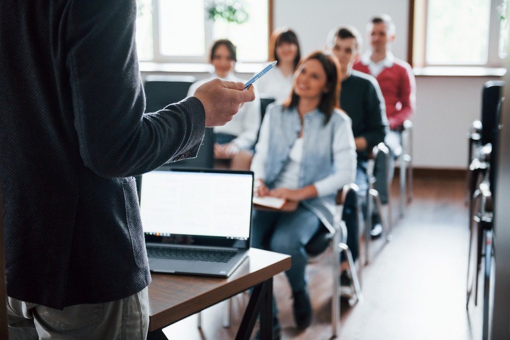 A Man Holding A Pen In Front Of A Group Of People During A Training Session On Cybersecurity.