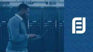 A man with a laptop in front of a server, working on cloud strategies.