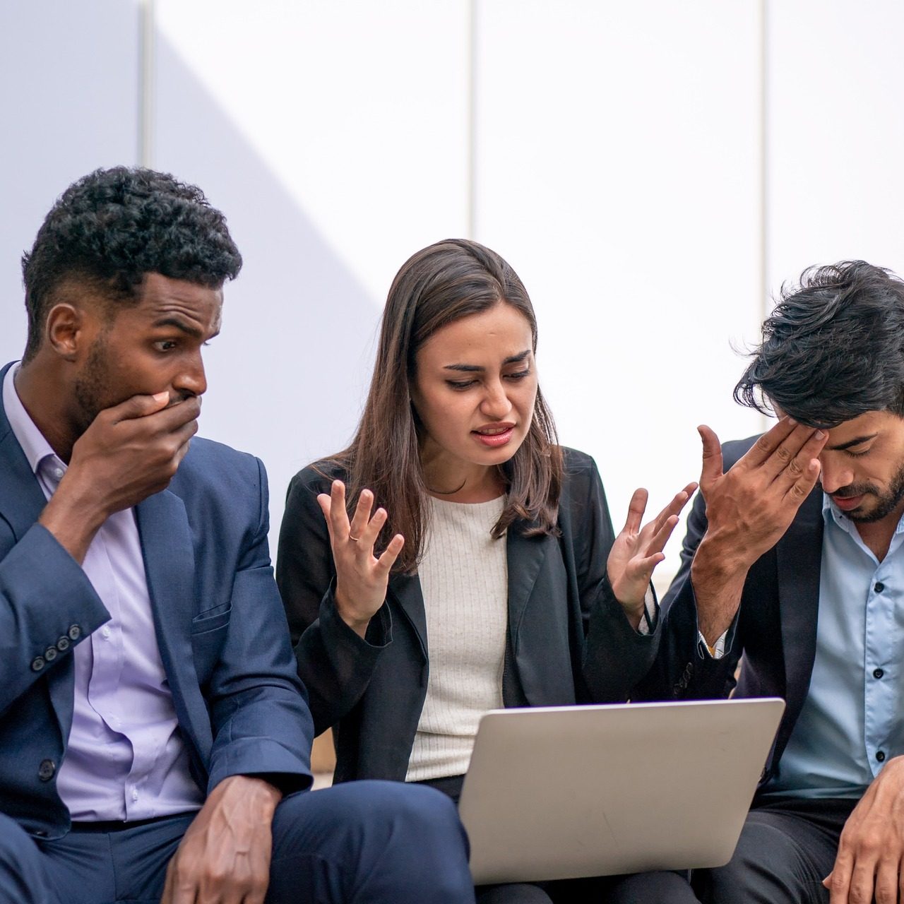 A group of business people conducting a case study while sitting on steps and examining a laptop.