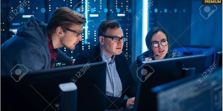 Three people managing IT infrastructure in a server room. Three people managing IT infrastructure in a server room.